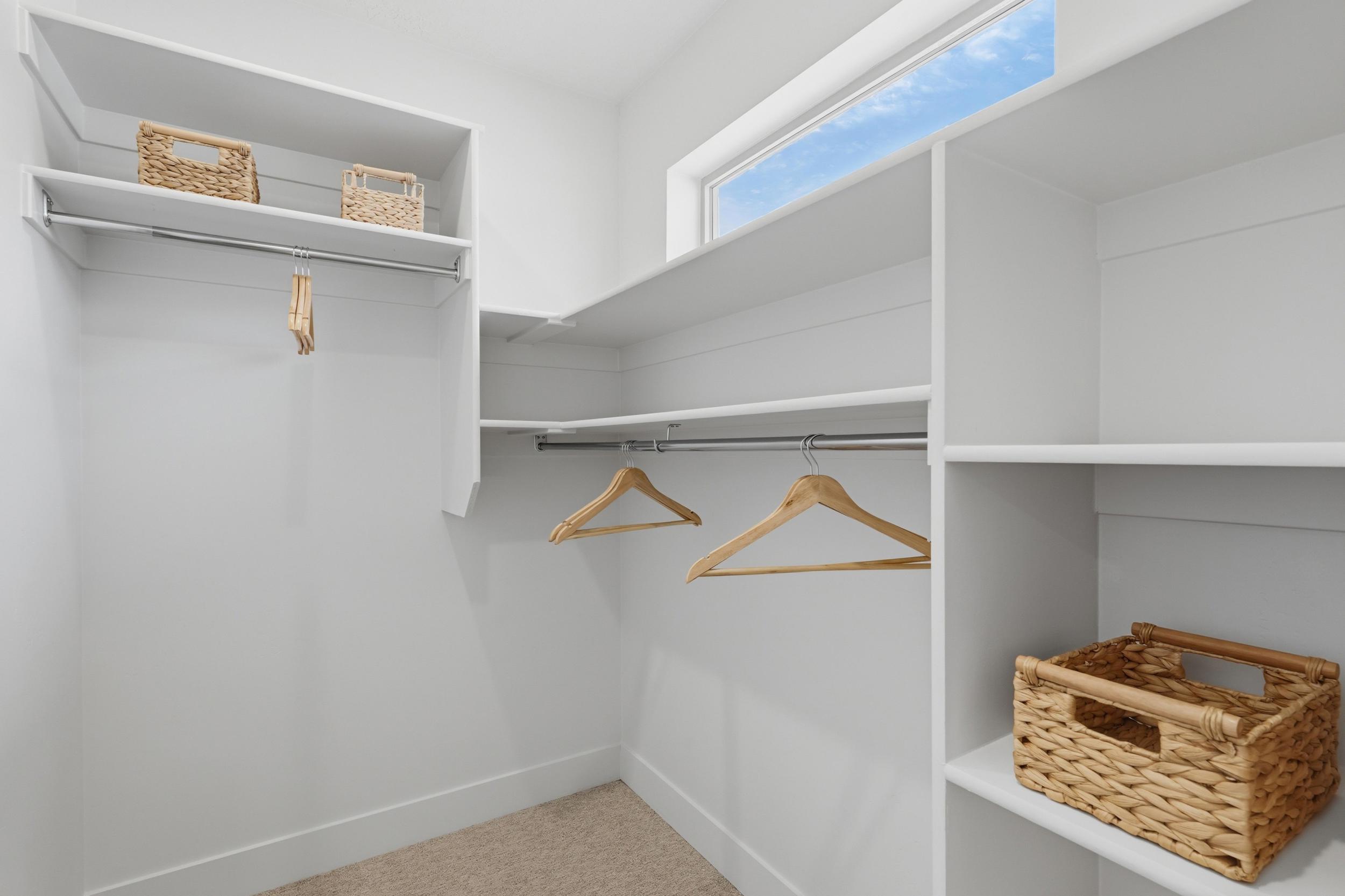 Walk-in closet featuring built-in shelving, chrome hanging rods, and a high transom window
