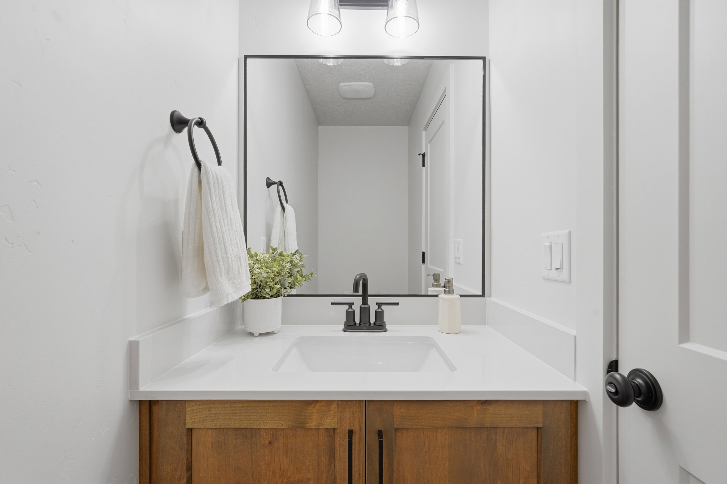 Bathroom vanity featuring a white rectangular sink, matte black faucet, and a large mirror with a black frame