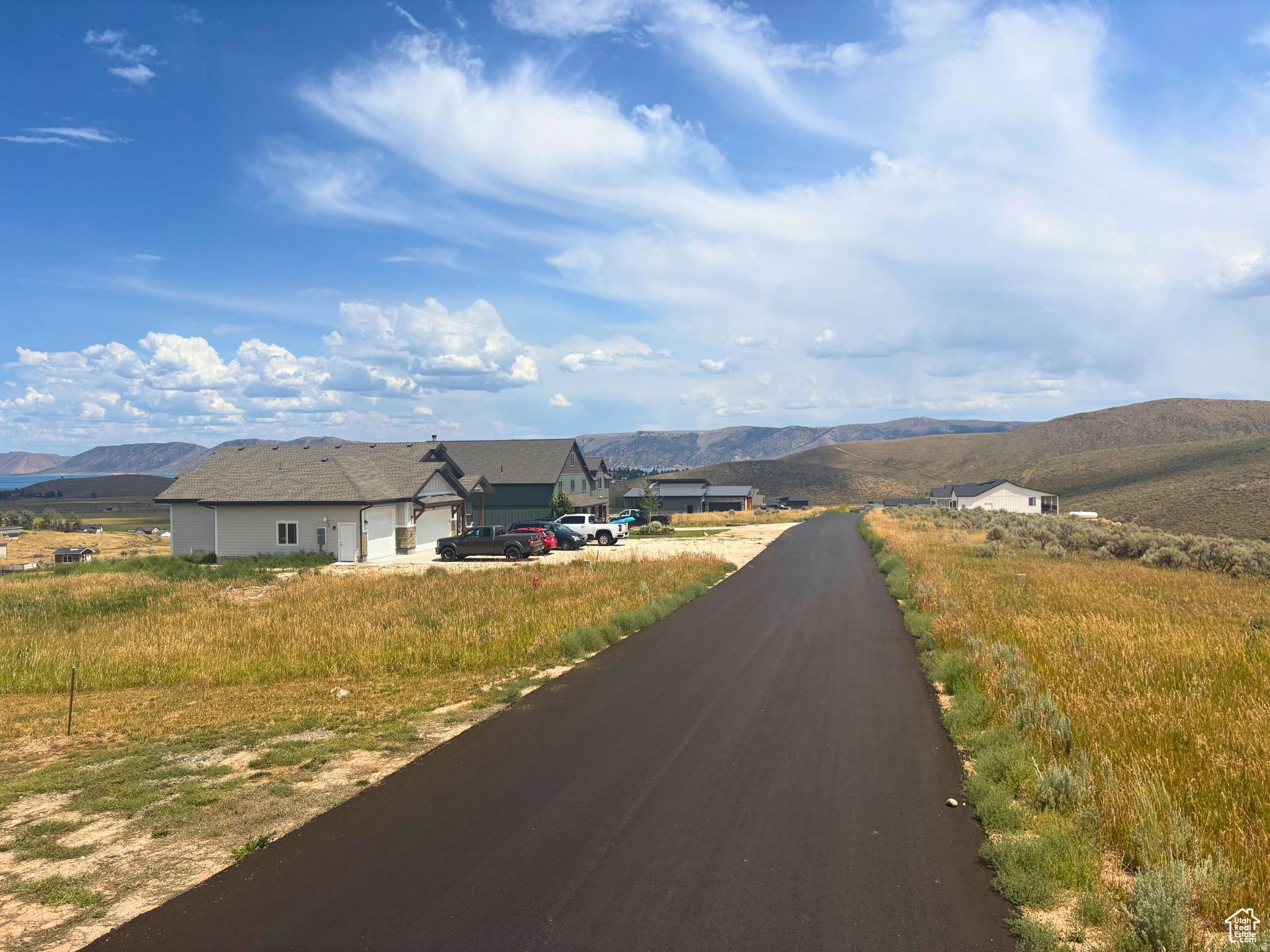 Paved roadway extending through a landscape of natural grasses and distant hills