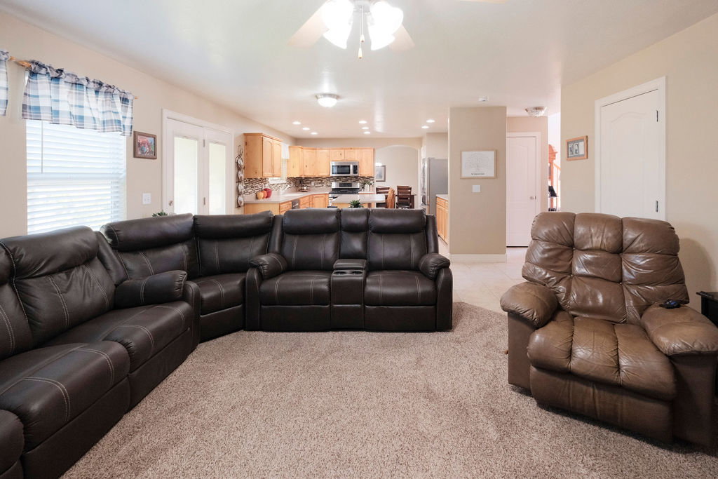 Open-concept living area featuring neutral-toned walls, textured carpeting, and recessed lighting