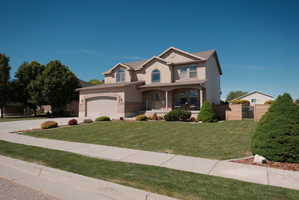 Two-story property featuring a stucco and brick exterior, an arched entryway, a covered porch, a two-car garage, and a manicured front lawn
