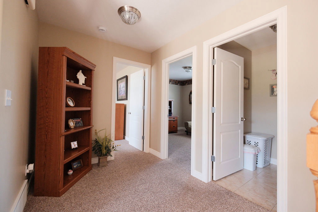 Hallway featuring plush carpeting, warm neutral wall tones, white trim, and a flush-mount ceiling light fixture