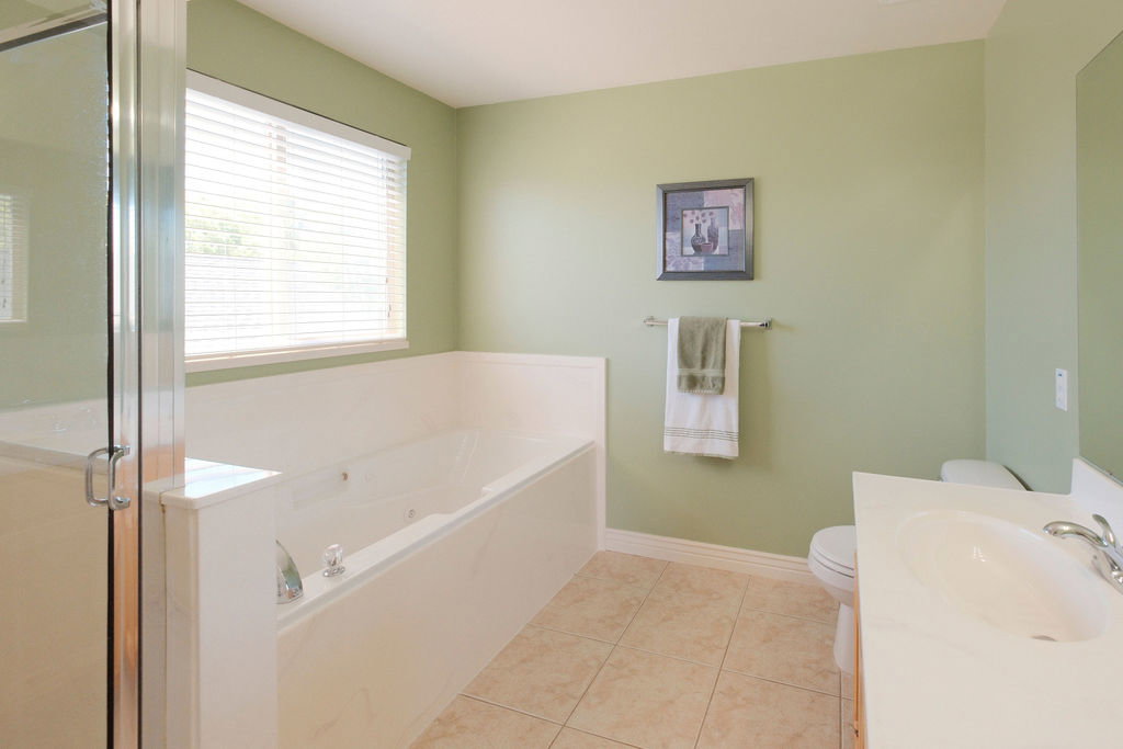 Bathroom featuring a built-in soaking tub with jets, a separate glass-enclosed shower, and a single vanity with a white countertop