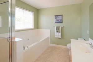 Bathroom featuring a built-in soaking tub with jets, a separate glass-enclosed shower, and a single vanity with a white countertop