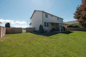 Expansive green lawn with a covered patio area and partial privacy fencing