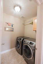 Dedicated laundry area featuring ceramic tile flooring, a wall-mounted drying rod, and a built-in upper cabinet