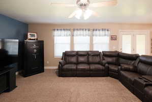 Spacious room featuring neutral carpeting, a ceiling fan, and multiple windows with blinds