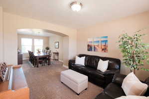 Expansive living area featuring neutral carpeting and an arched entryway to the dining space