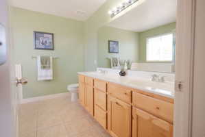 Bathroom featuring a dual-sink vanity with wood-finish cabinetry and a spacious countertop