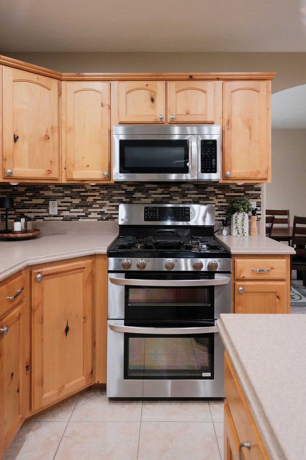 Stainless steel double oven range with a coordinating microwave and an intricate mosaic tile backsplash
