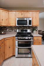 Stainless steel double oven range with a coordinating microwave and an intricate mosaic tile backsplash
