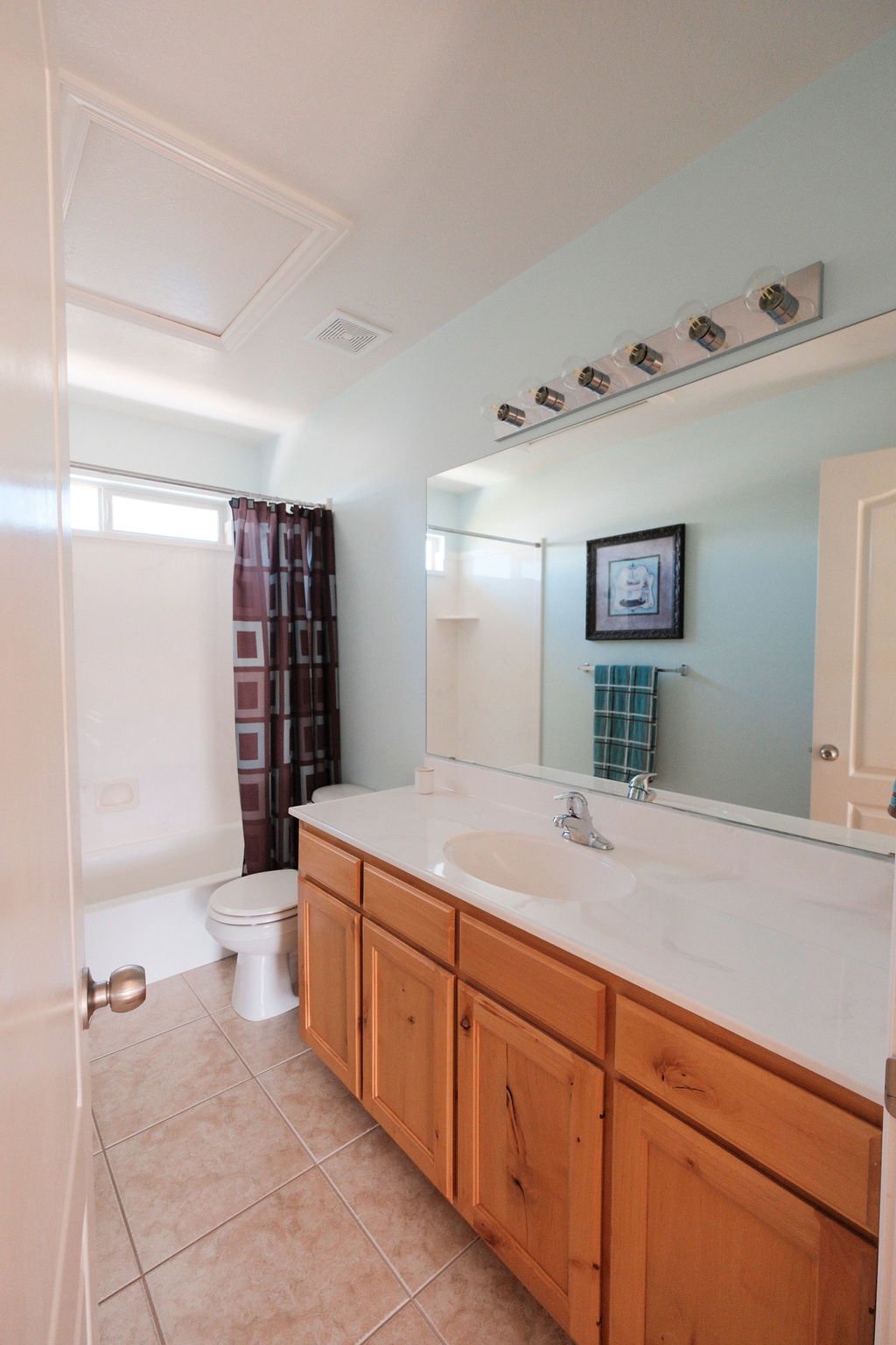 Bathroom featuring a single vanity with wood-finish cabinetry, a white countertop, and an integrated sink