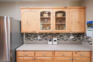 Light wood-finish cabinetry featuring both solid and glass-front doors