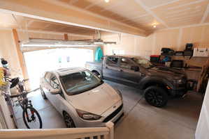 Spacious two-car garage with overhead lighting, unfinished drywall, and an open garage door