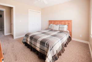 Carpeted room featuring a white ceiling fan, light beige walls, white baseboards, and a bi-fold closet