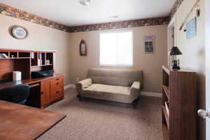 Carpeted room featuring a window with blinds, light tan walls, and white baseboards