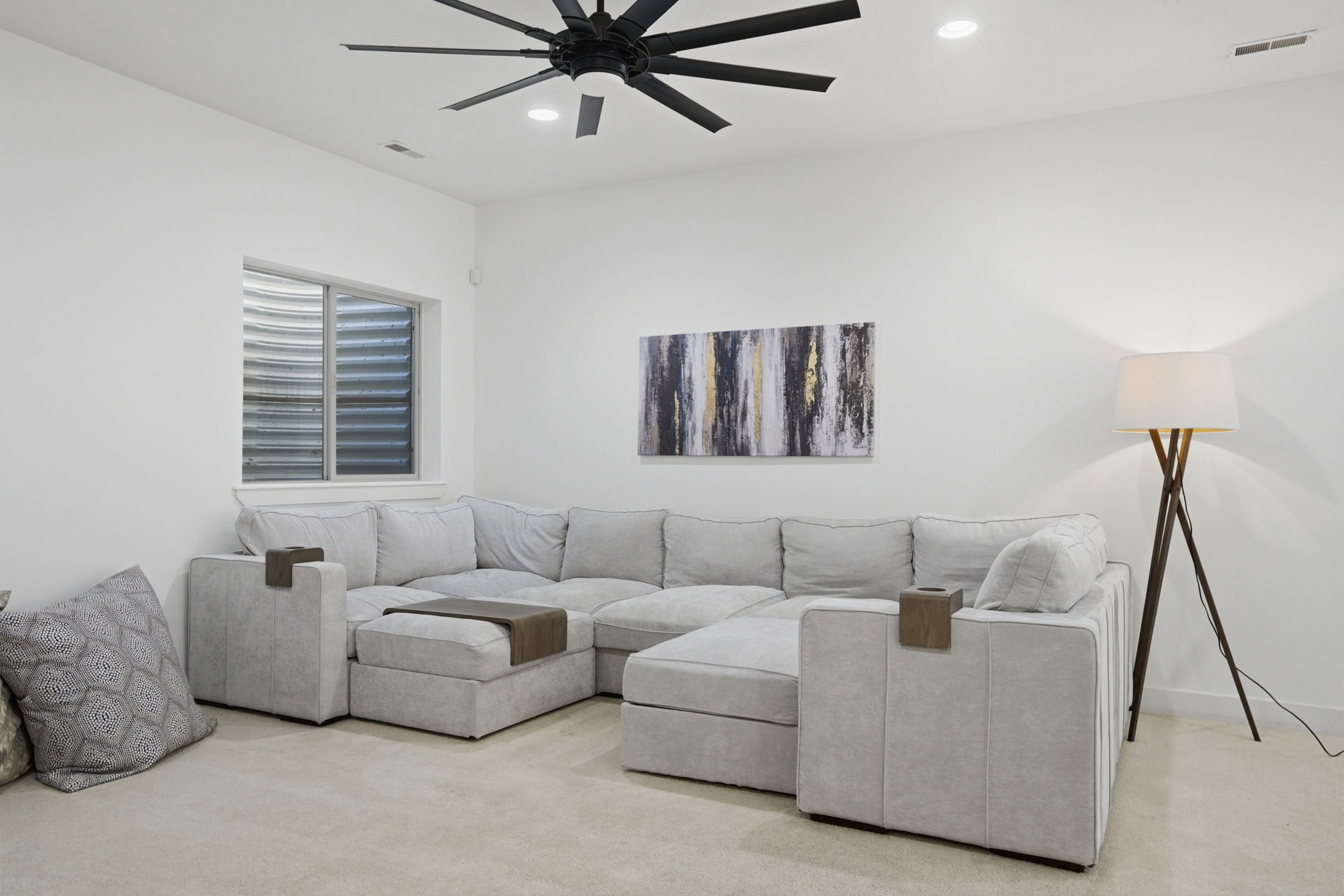 Spacious family room area featuring a large window, recessed lighting, and a modern ceiling fan