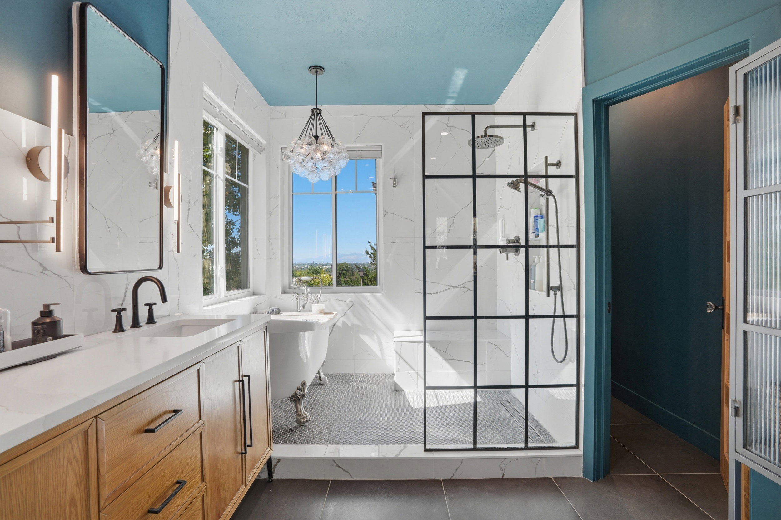 Porcelain tiled bathing area and damp-rated bubble chandelier above clawfoot tub