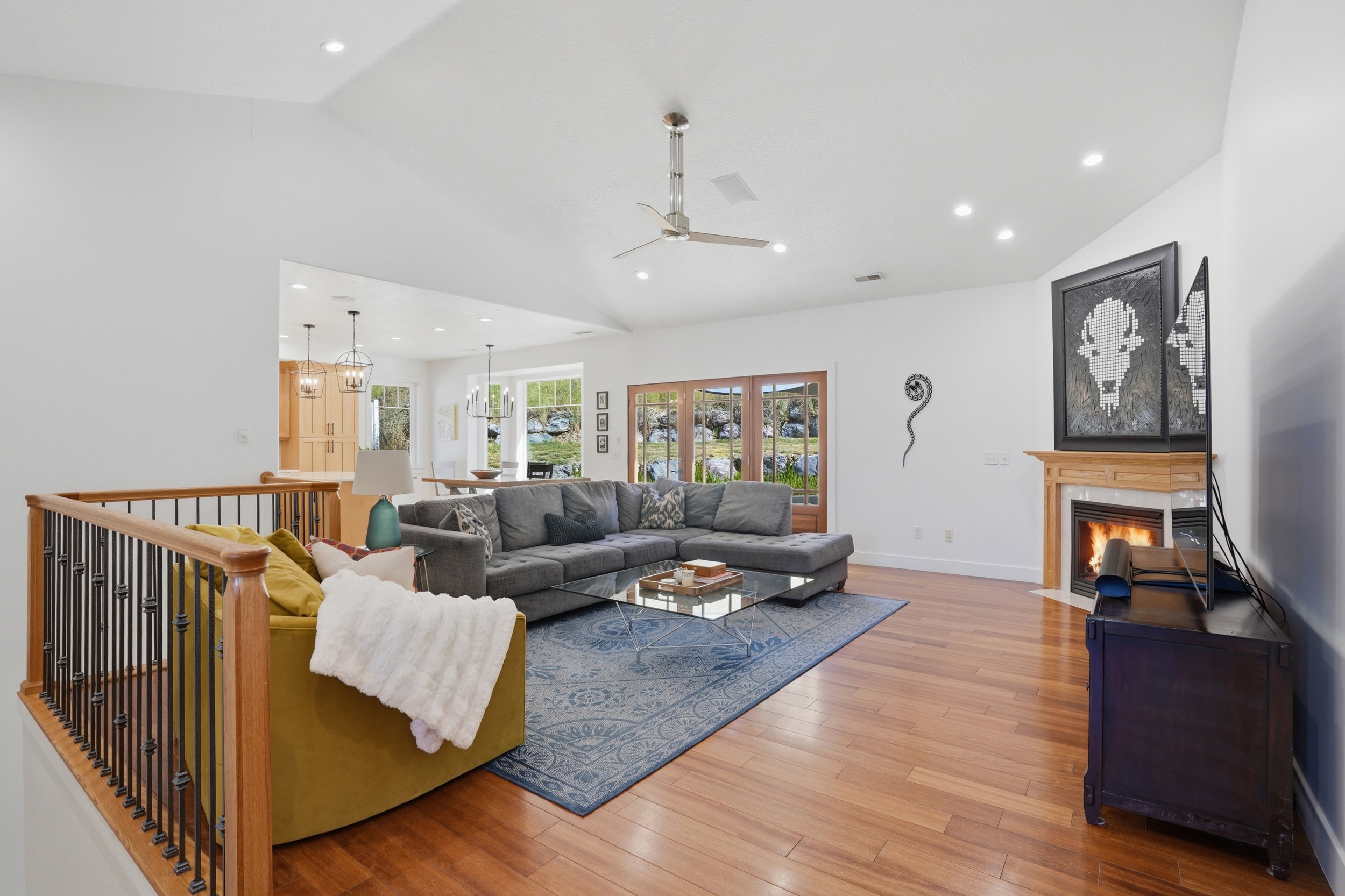 Freshly painted & spacious living area featuring high vaulted ceilings, recessed lighting, wood-finish flooring, a fireplace with a wood mantle, and French doors