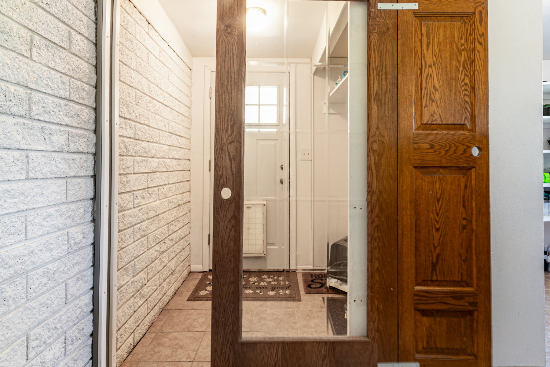 Tiled back entry featuring a wooden sliding barn door, white painted brick wall, and overhead lighting