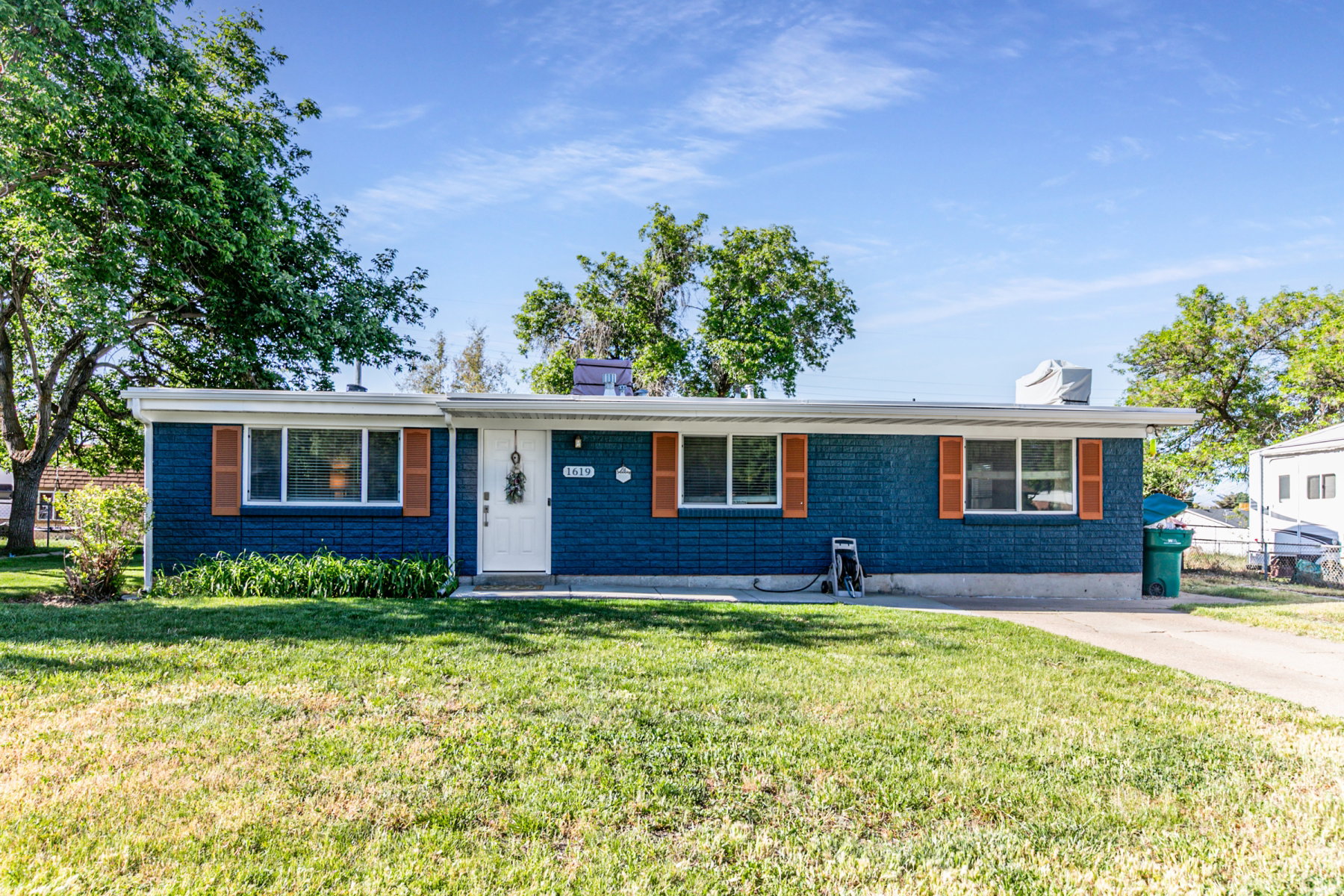 Ranch-style residence featuring a blue brick exterior with white trim and wooden shutters