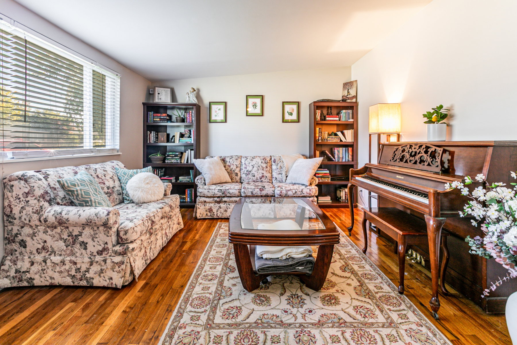 Living area featuring wood flooring, a large window with blinds.