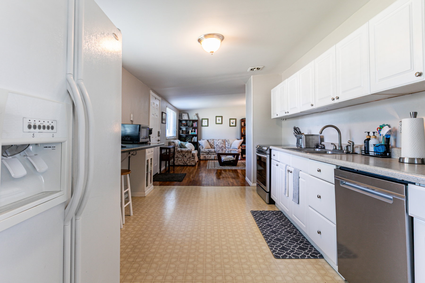 Kitchen featuring white cabinetry, a stainless steel dishwasher, a stainless steel sink with a gooseneck faucet, light-toned countertops.