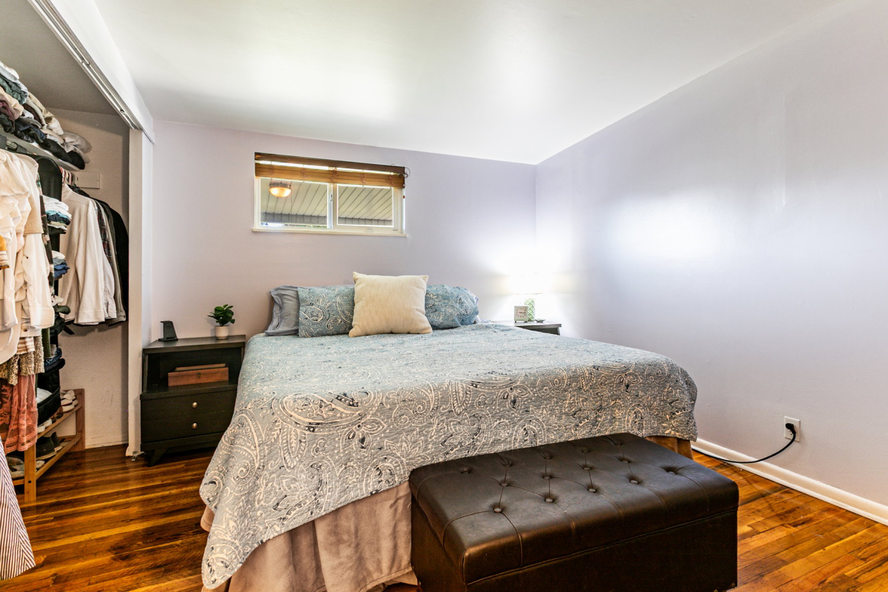 Bedroom featuring wood flooring, a window, a large closet and attached bath