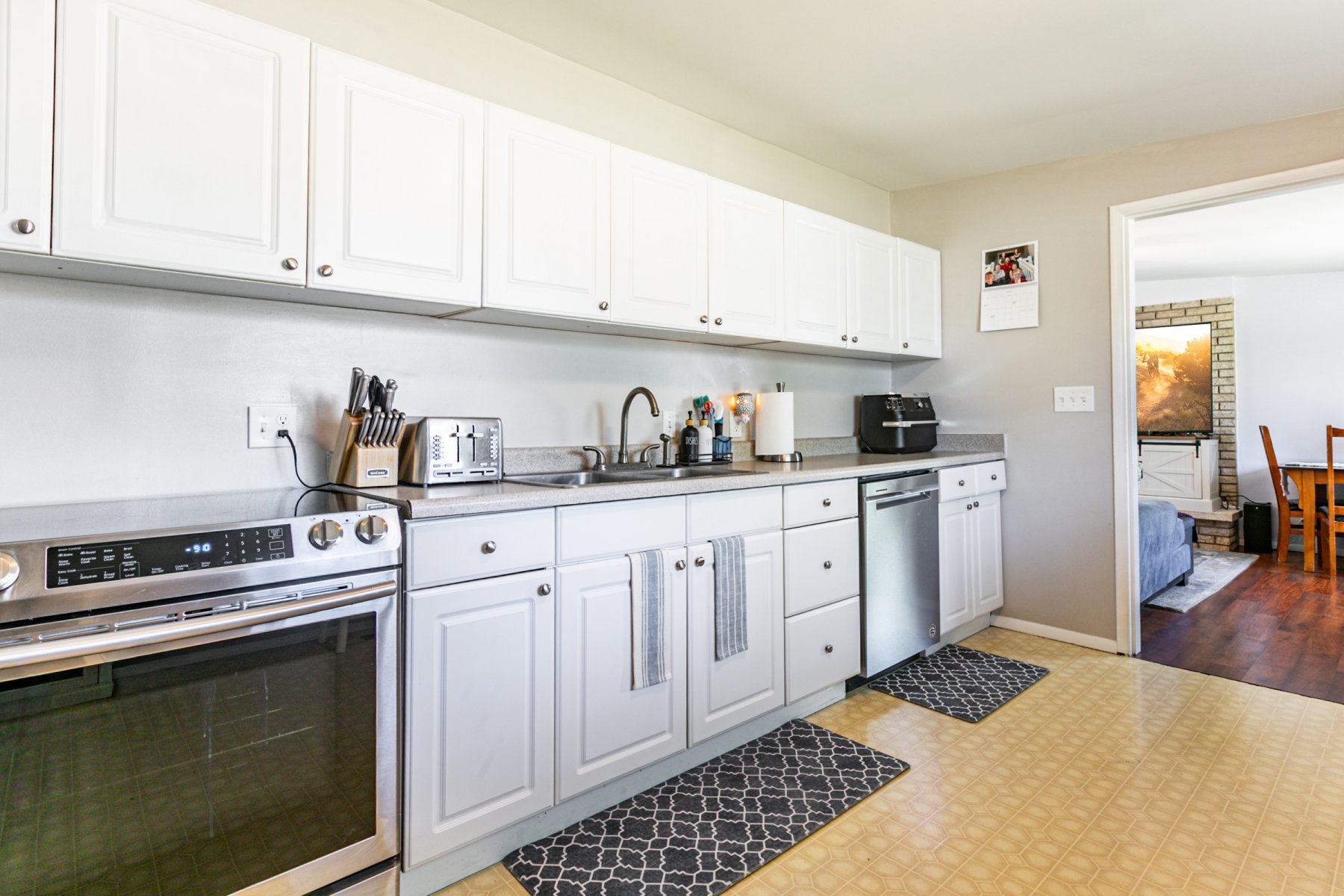 Kitchen featuring white cabinetry, light countertops, stainless steel appliances.
