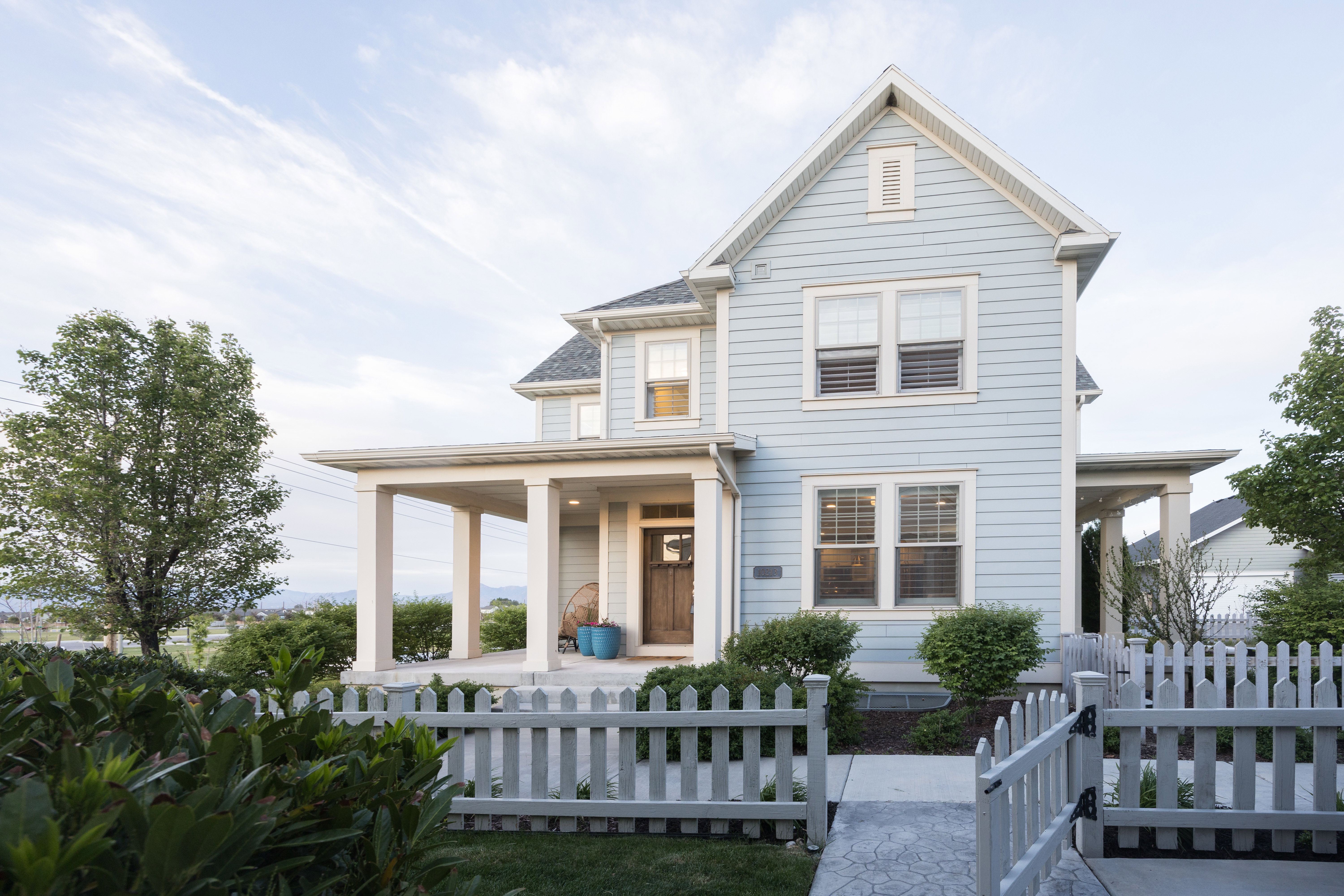 Light blue siding exterior featuring a covered porch with substantial columns, a gabled roofline, and white trim