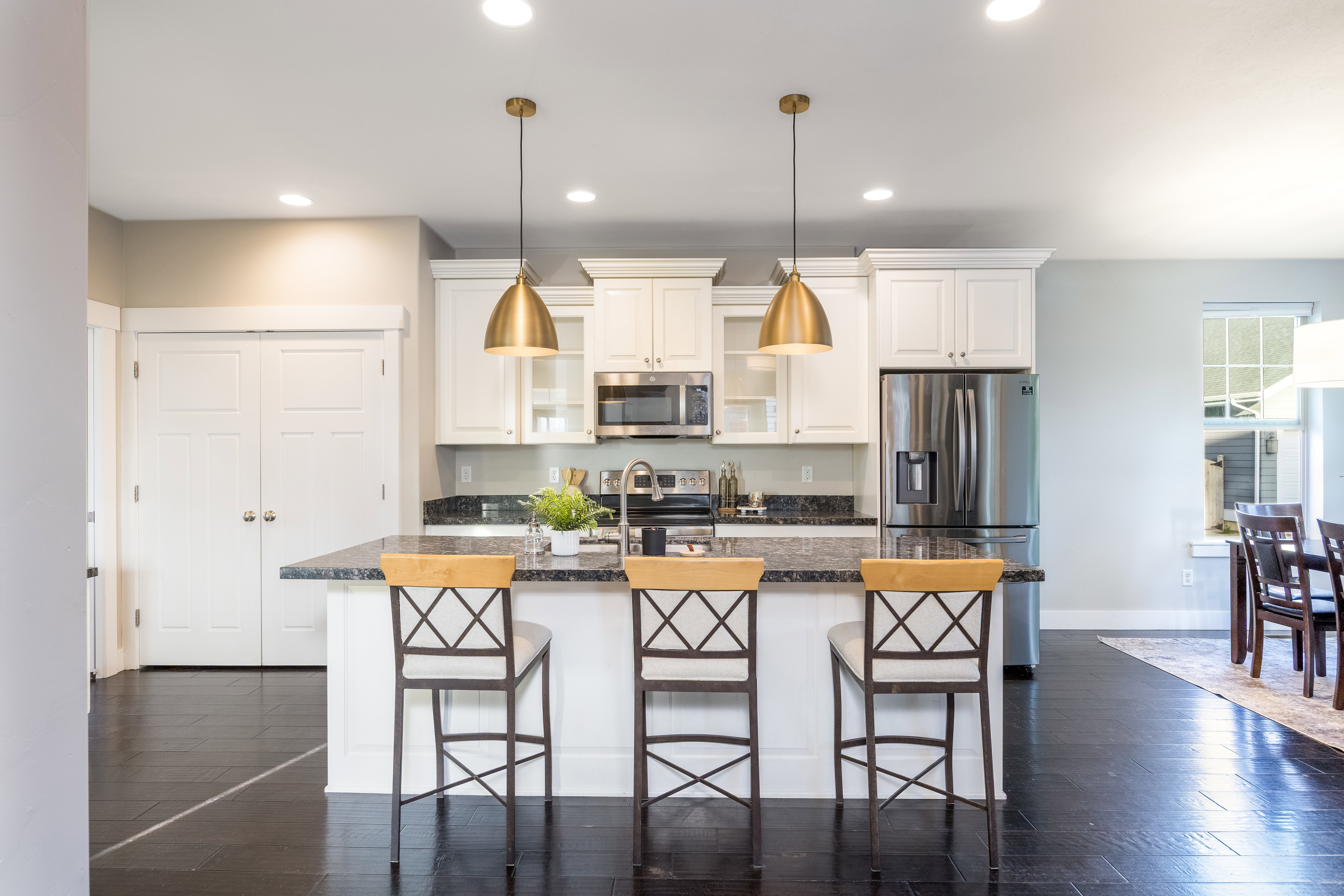 Kitchen featuring white shaker cabinetry, dark granite countertops, stainless steel appliances, and dark wood-finish flooring