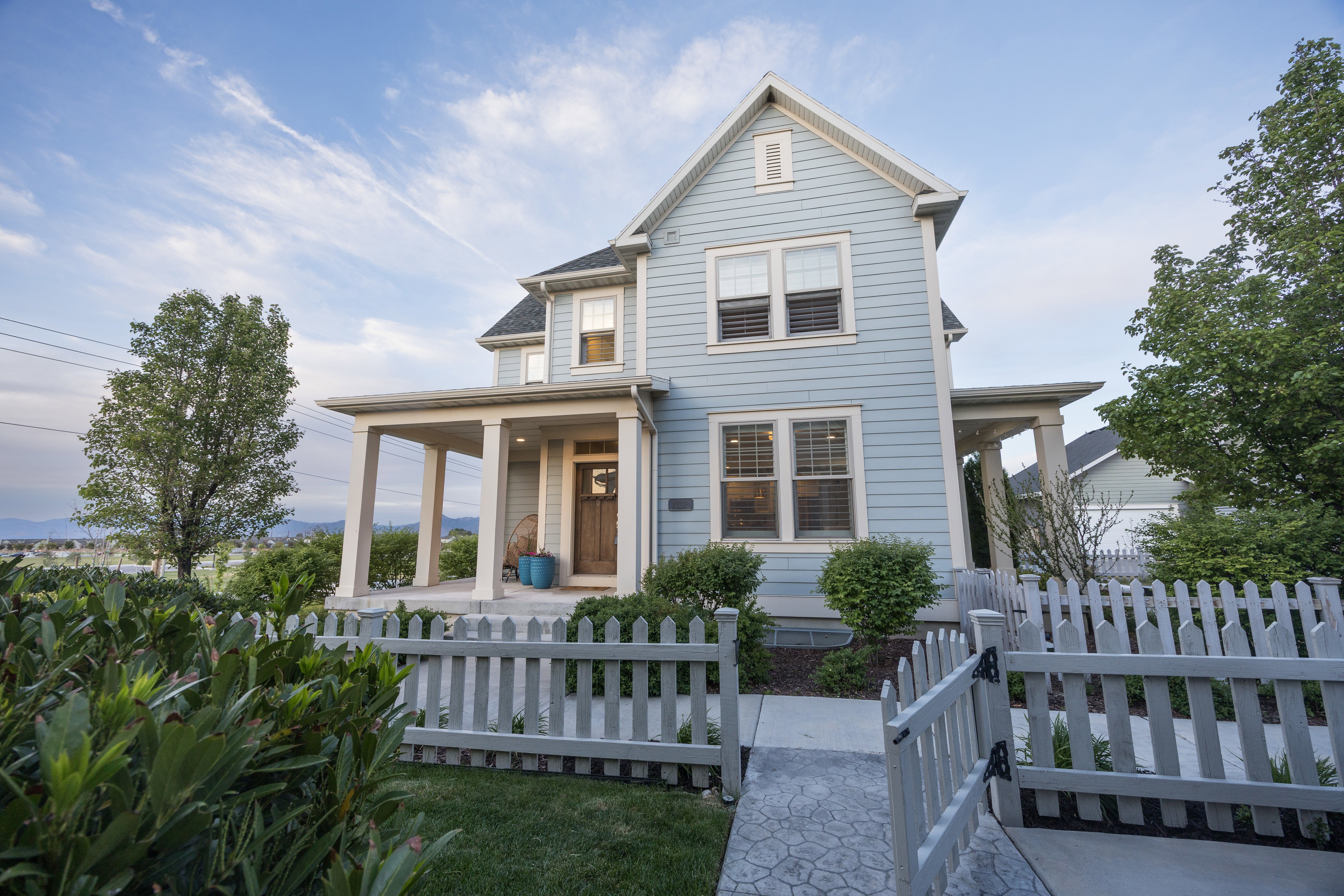 Two-story residence featuring light blue siding, a covered front porch with substantial columns, and a dark wood-finish entry door