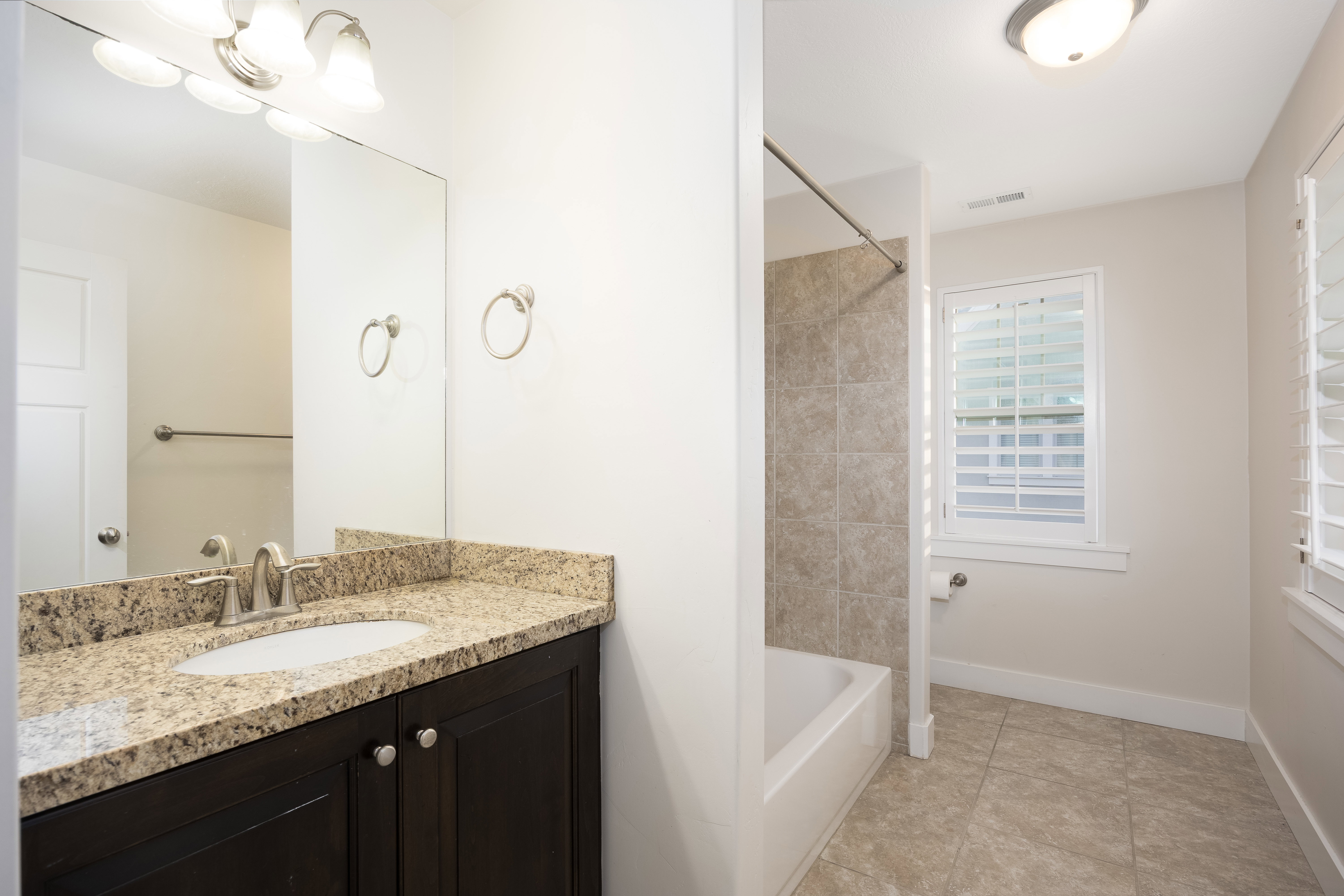 Bathroom featuring a granite-finish vanity, undermount sink, and dark wood-finish cabinetry