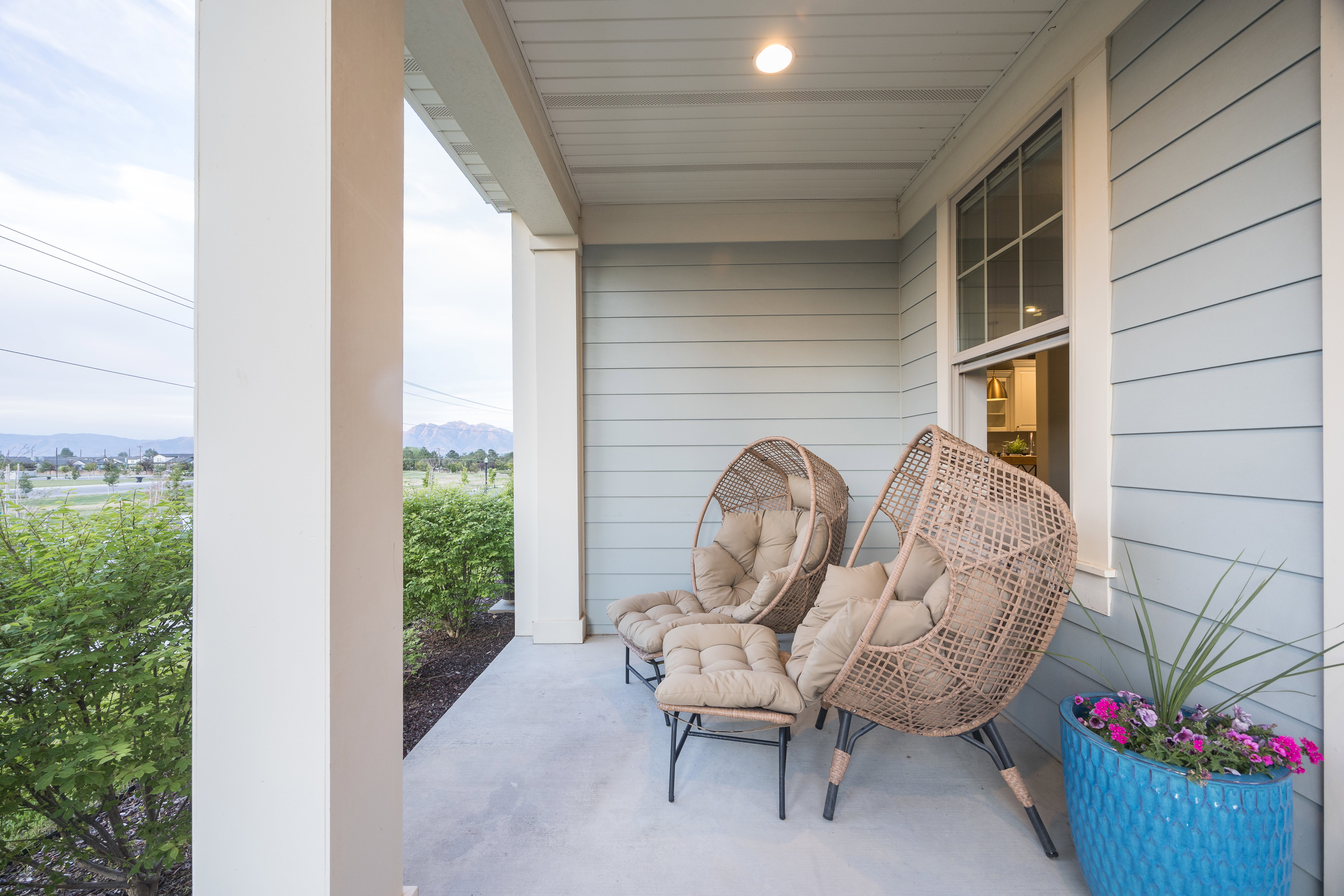 Covered front porch featuring pale blue siding, white trim, and recessed lighting