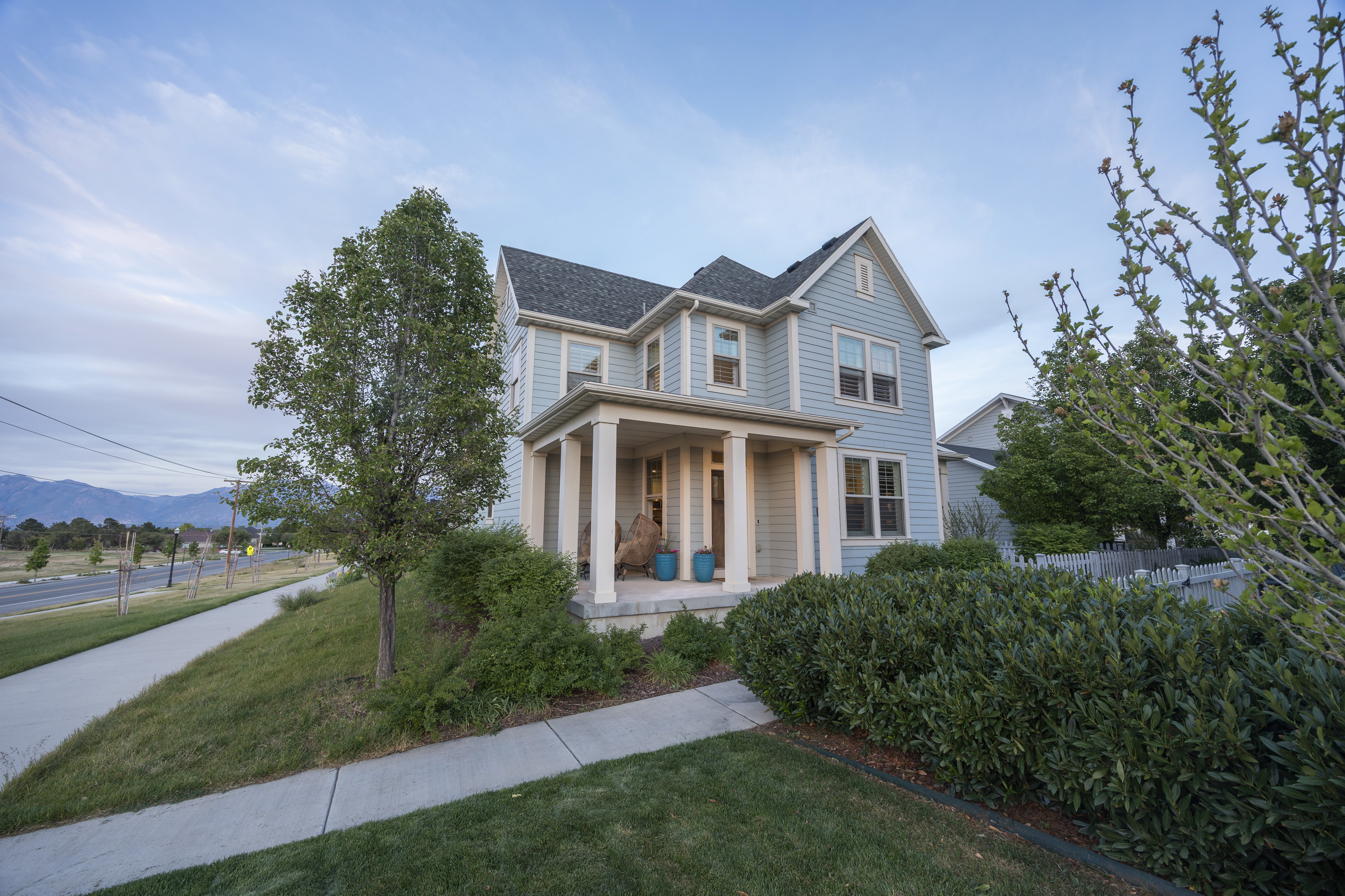 Two-story residence featuring light blue siding, a covered porch with white columns, and a gray shingle roof