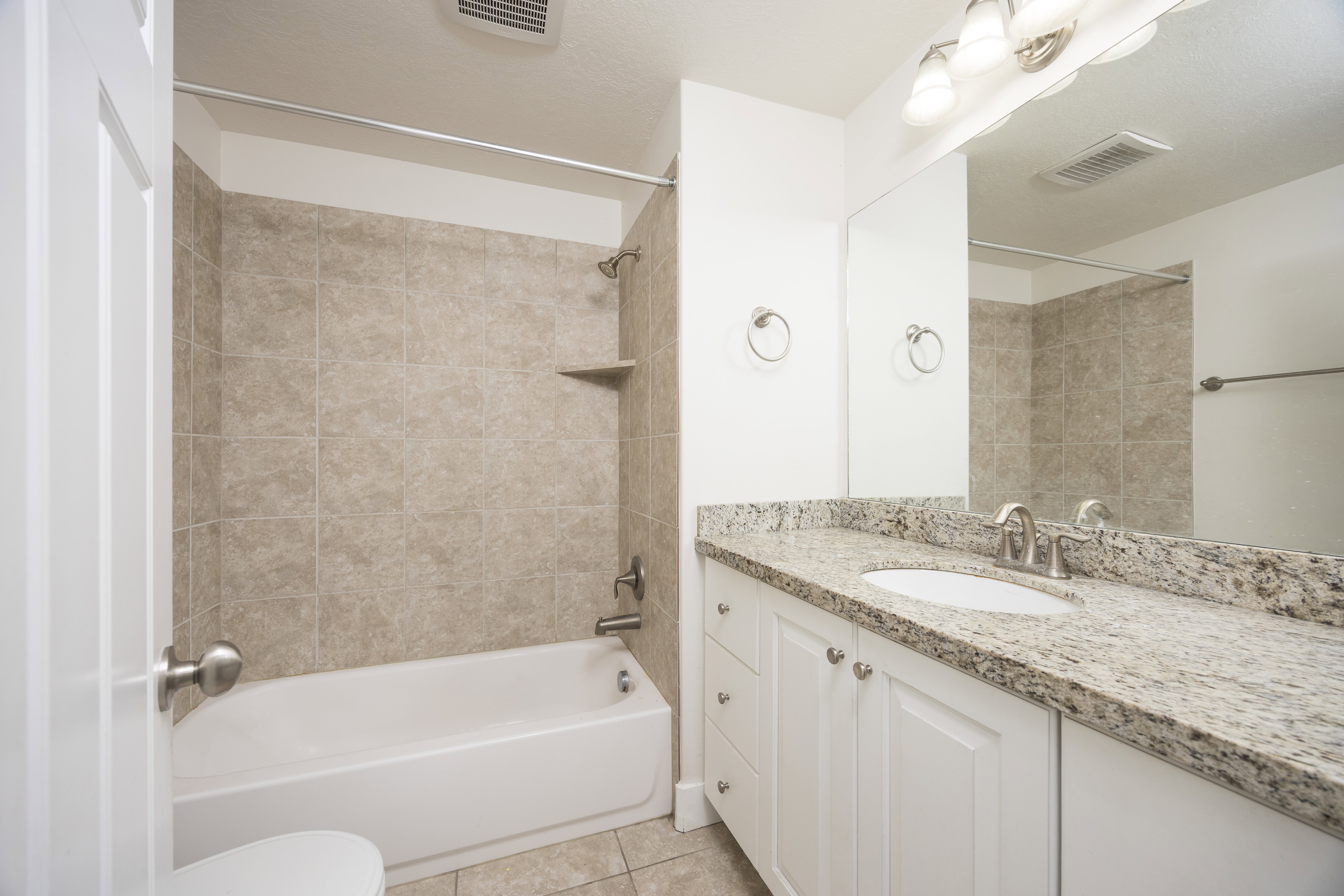 Bathroom featuring a white bathtub, beige tile surround, and a built-in corner shelf