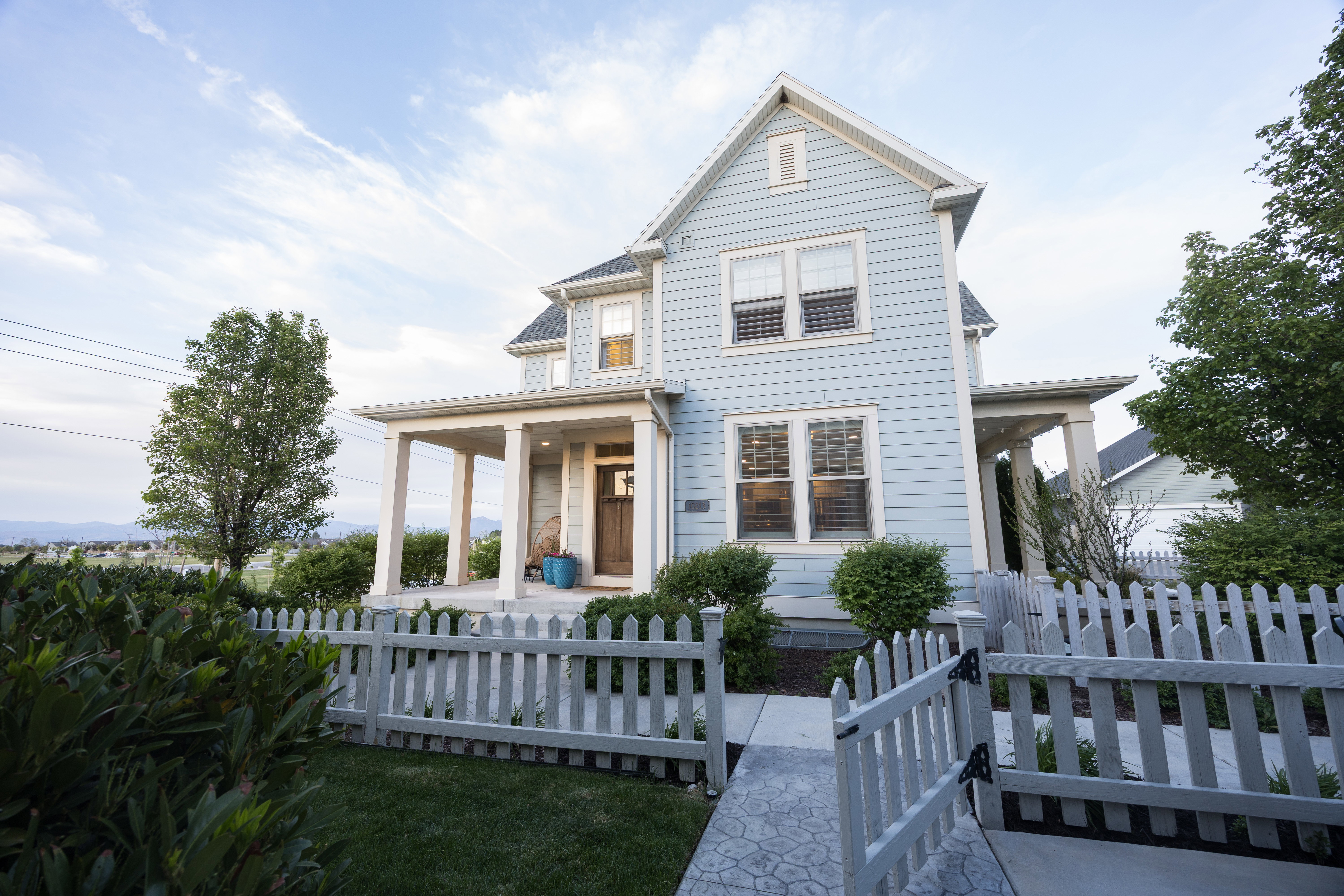 Light blue siding exterior featuring a covered porch, white trim, and a gabled roofline