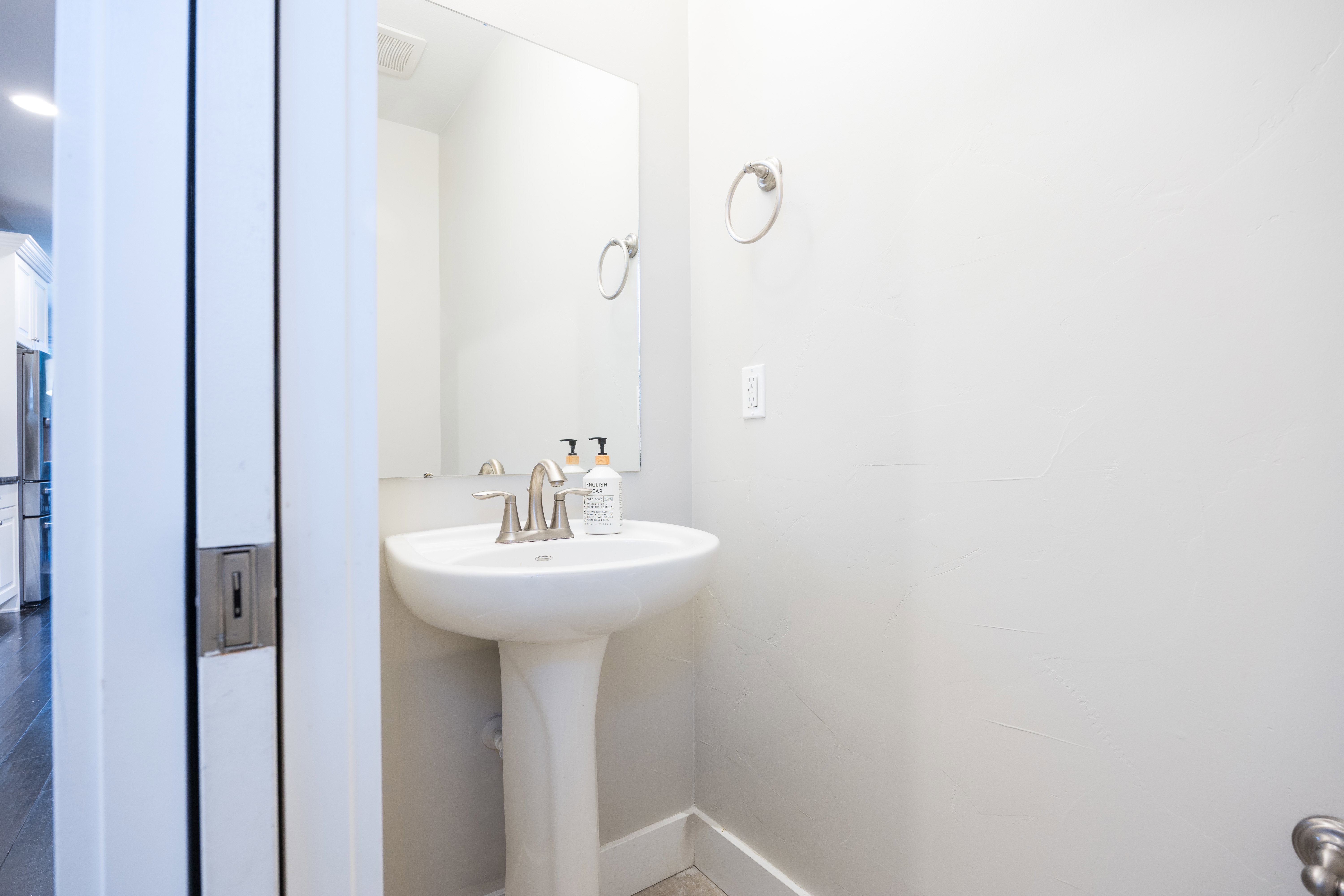 White pedestal sink with a contemporary brushed nickel faucet and a wall-mounted mirror