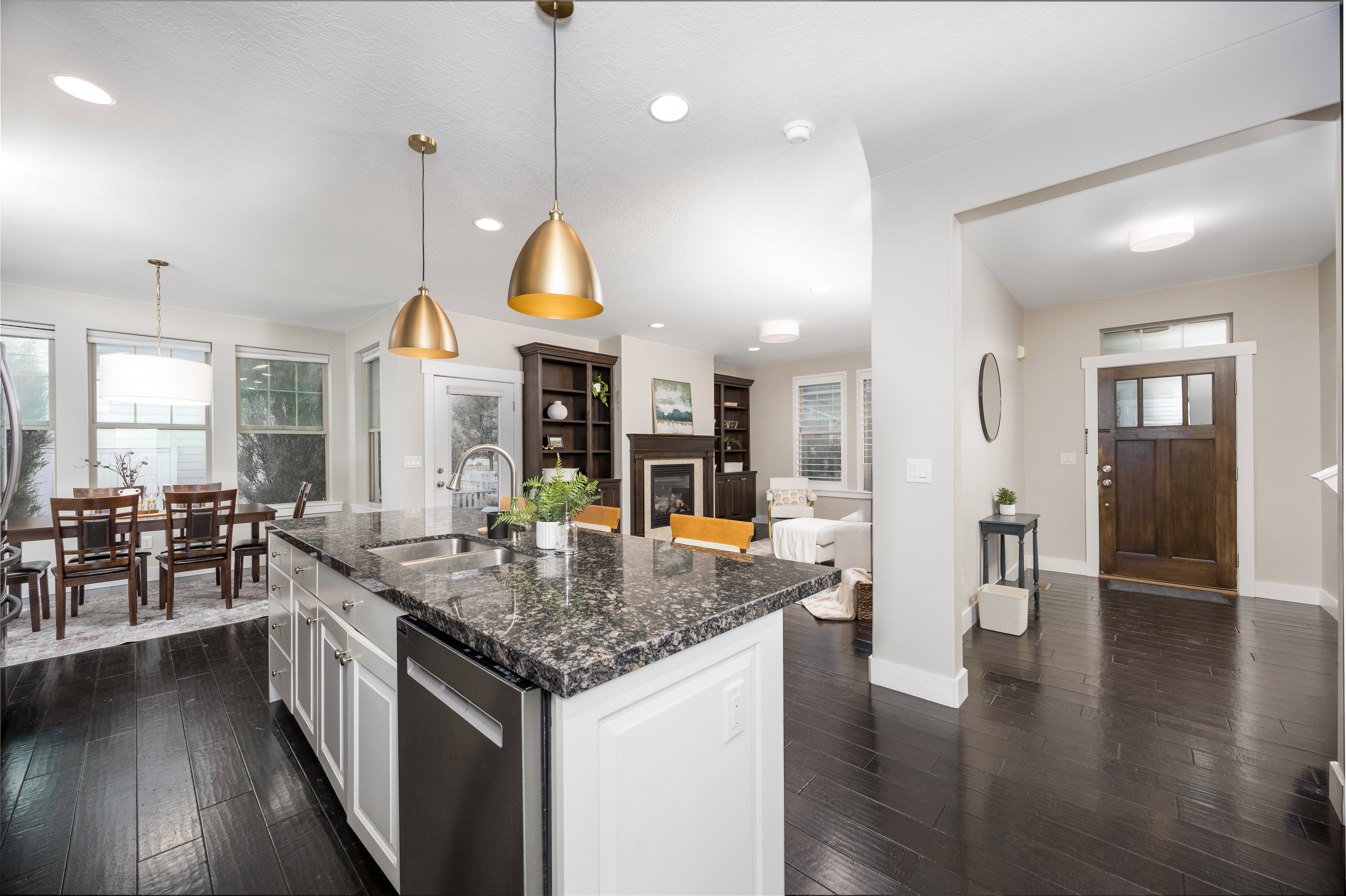 Open-concept kitchen featuring an island with granite-finish countertop, dual pendant lighting, and stainless steel appliances