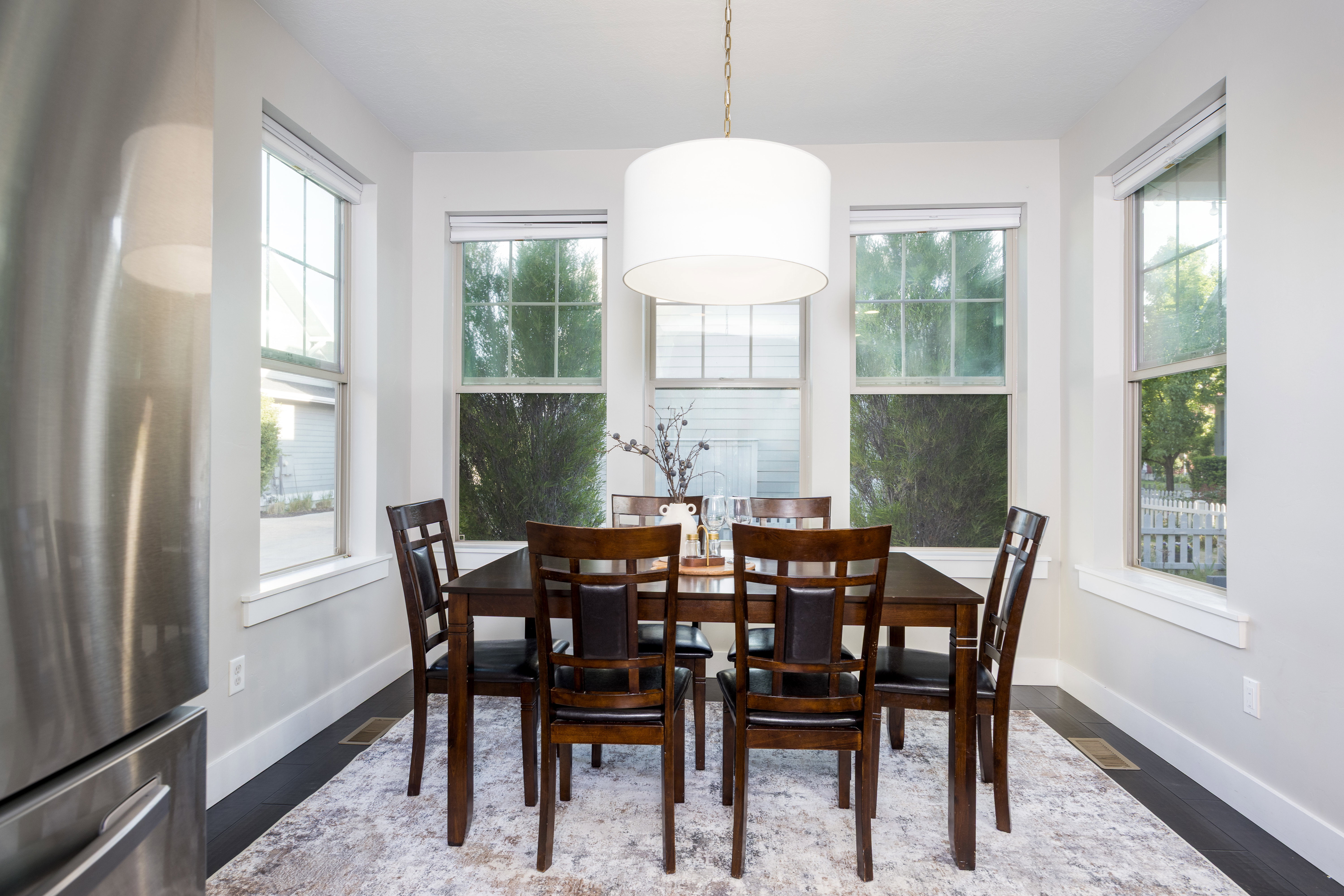Dining area featuring dark wood-finish flooring, light-toned walls, and a contemporary drum pendant light fixture