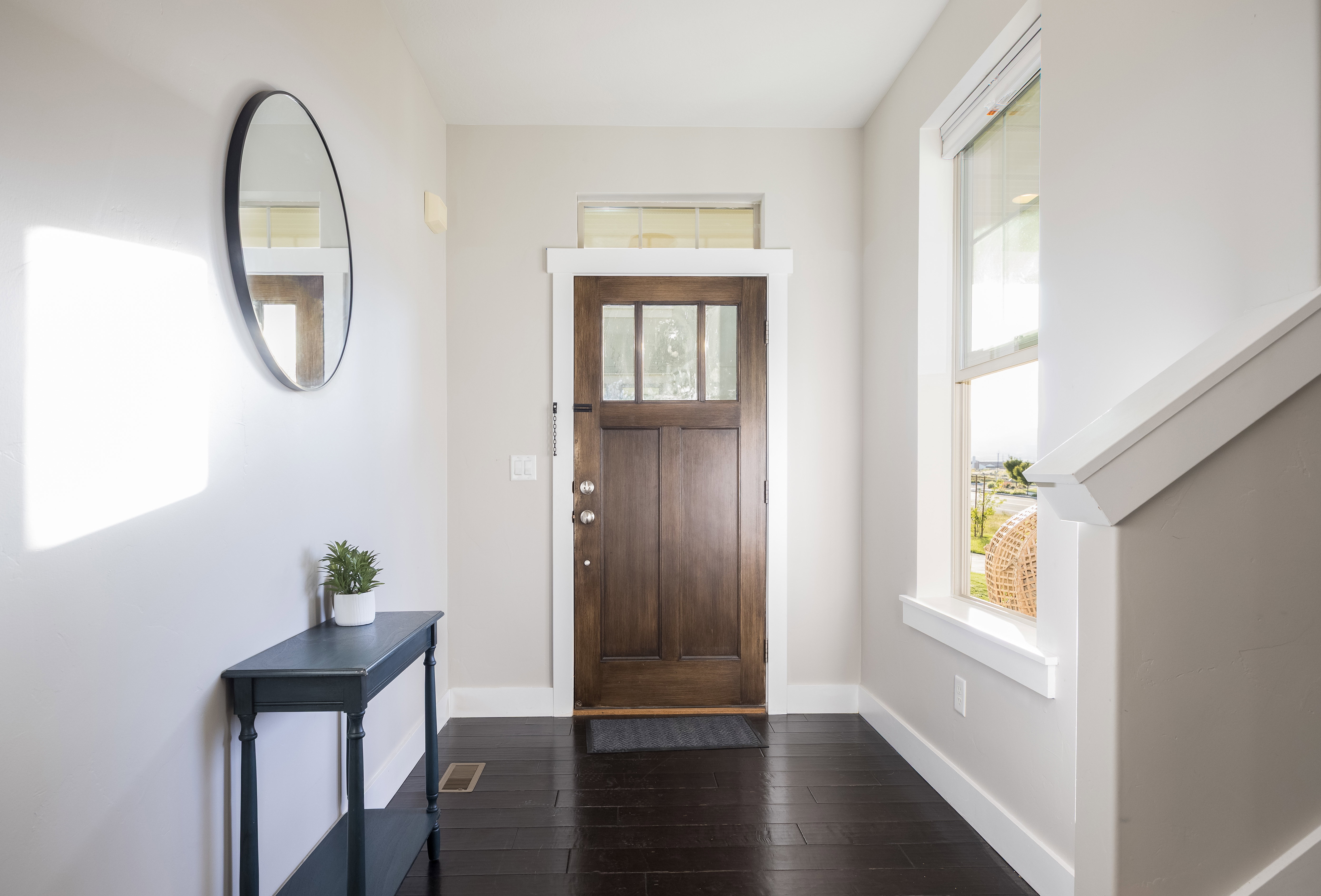 Entryway featuring a dark wood-finish door with glass panels, rich dark wood-finish flooring, a transom window, a side window, and white trim