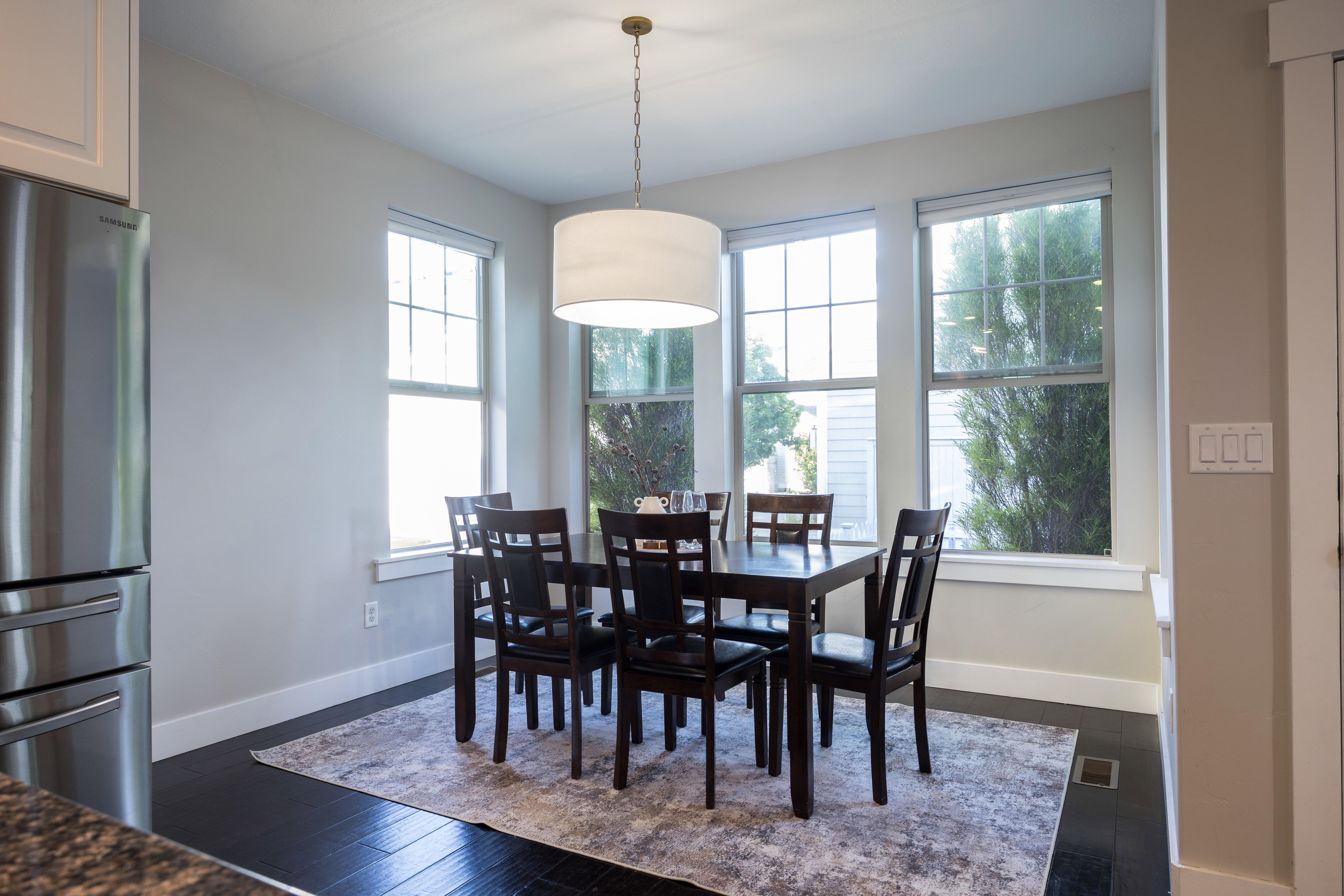 Dining area featuring dark wood-finish flooring and a contemporary drum pendant light fixture