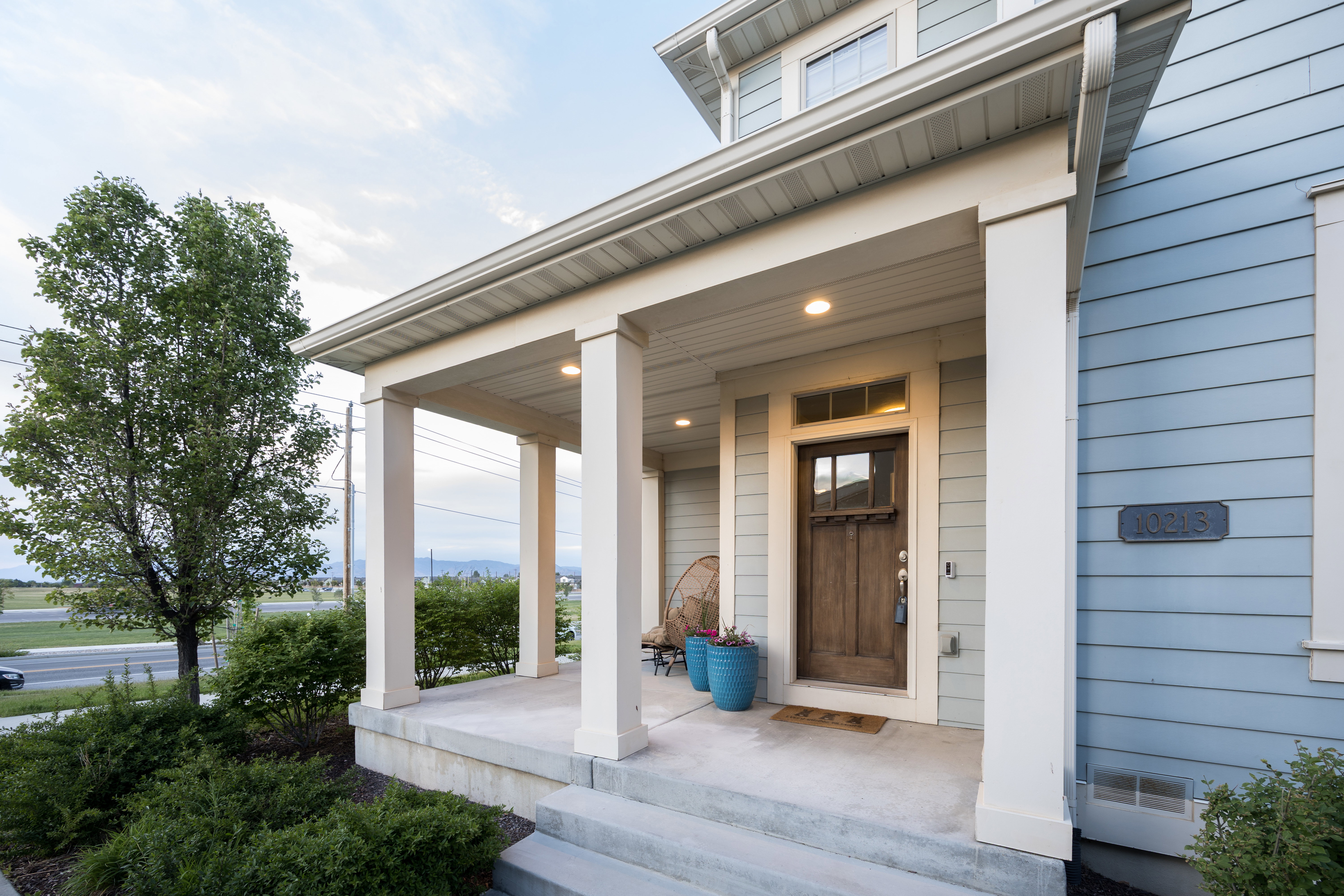 Covered front porch featuring robust columns and recessed lighting