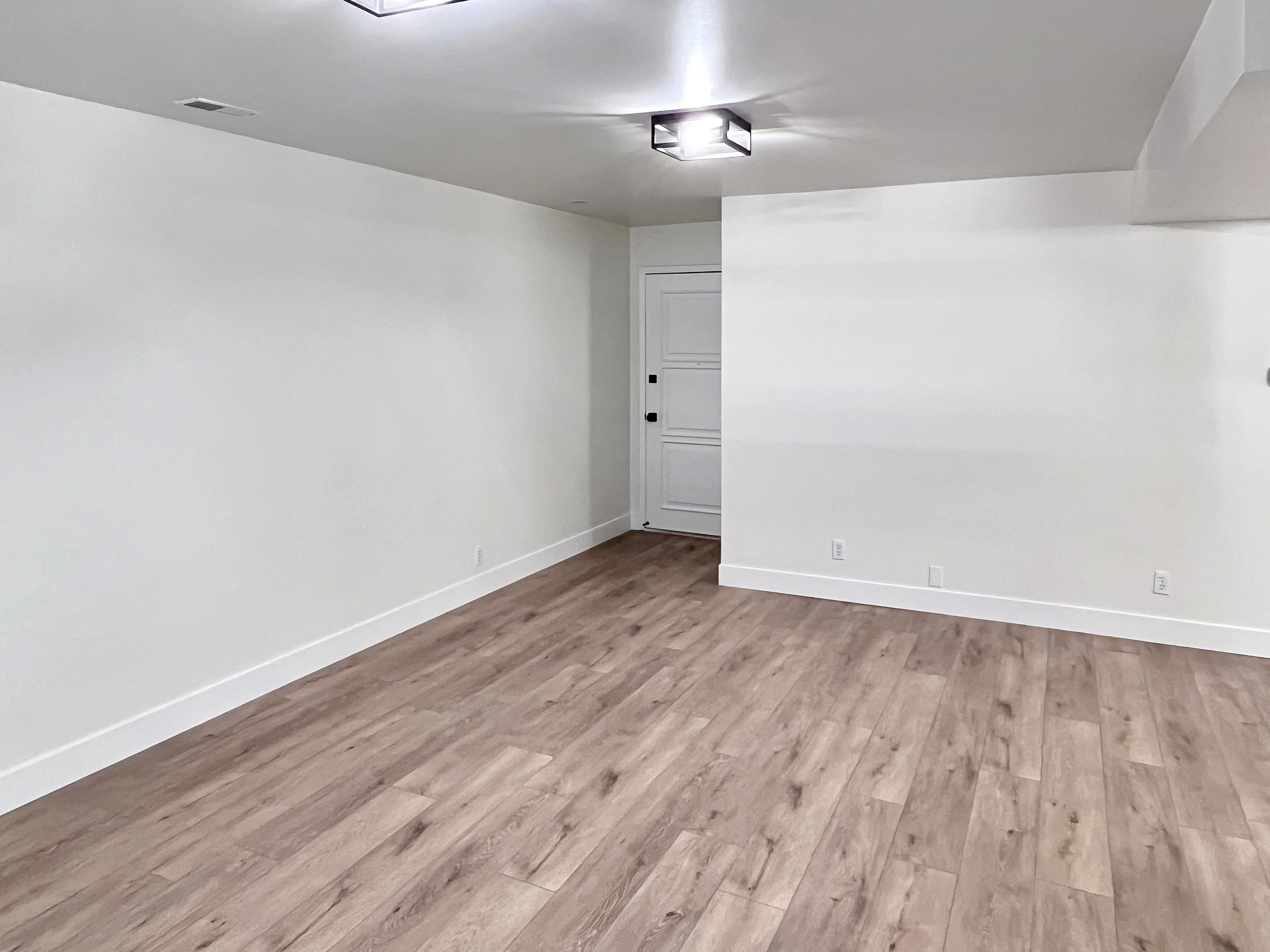 Living room featuring warm tones, fresh wood style flooring and newly painted timeless two-toned paint with large, modern baseboards
