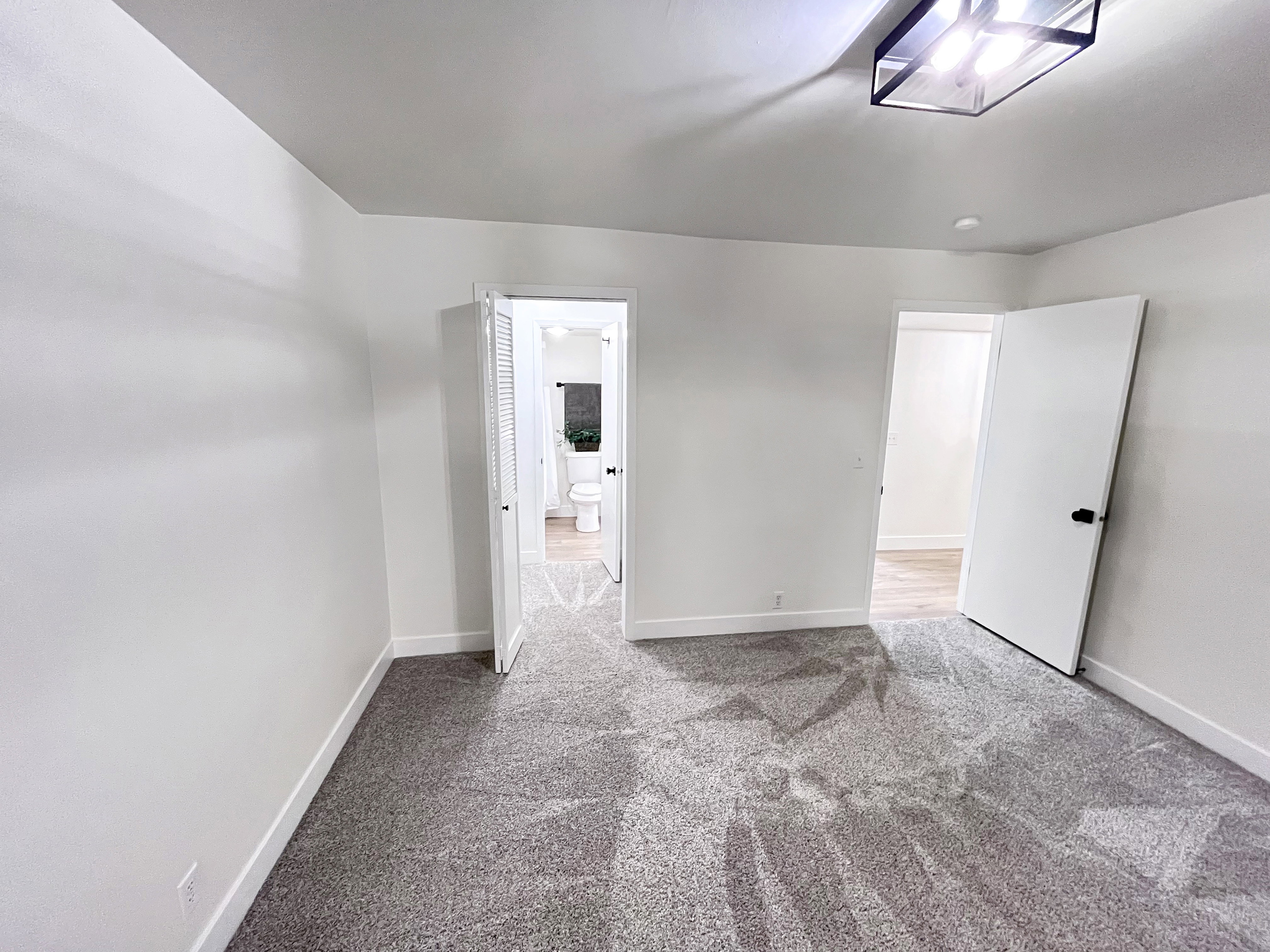 Second Bedroom featuring tall baseboards, cozy plush carpet, warm tones, and convenient bathroom access through a walk-in closet