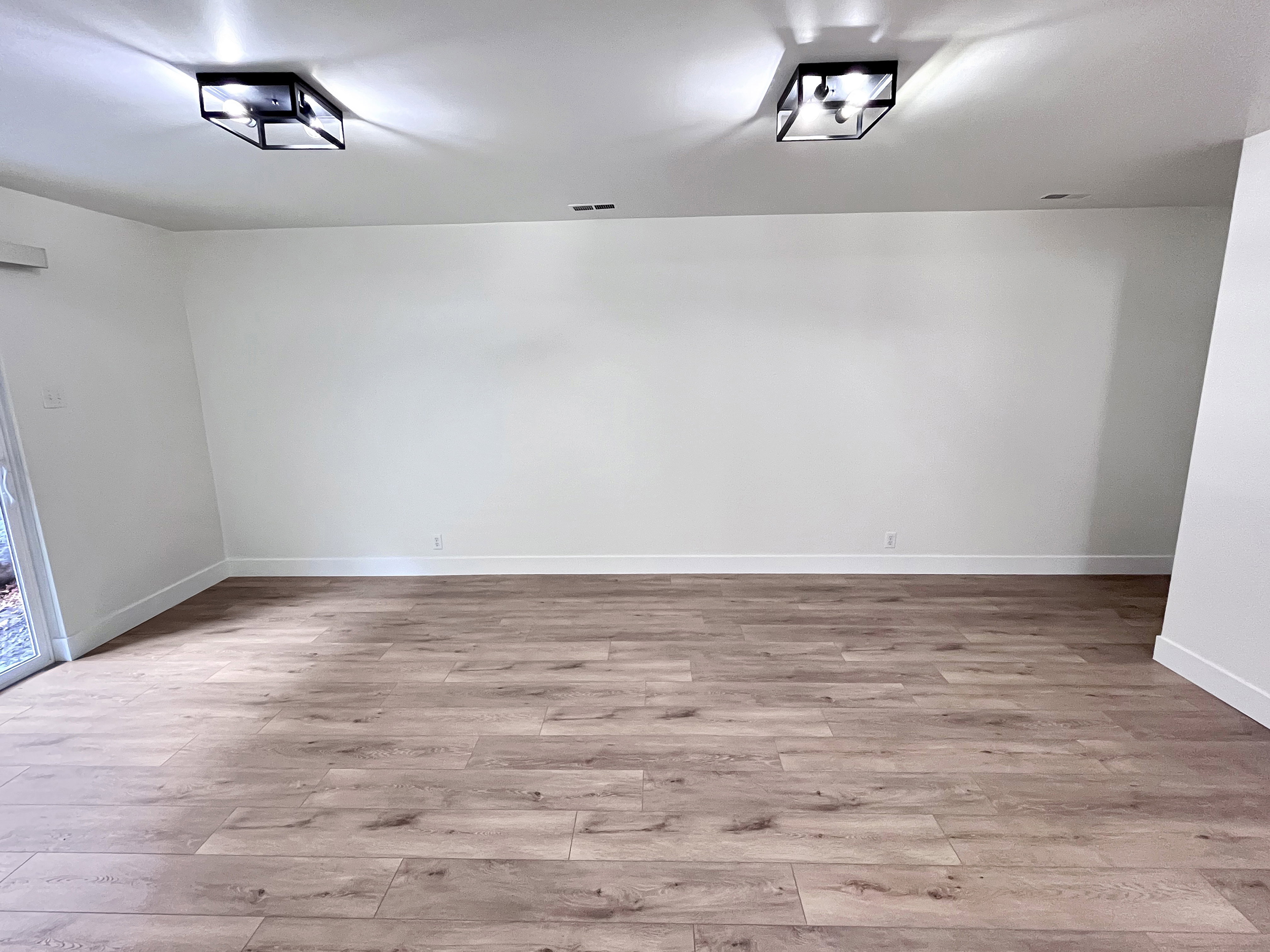 Living room featuring warm tones, fresh wood style flooring and newly painted timeless two-toned paint with large, modern baseboards