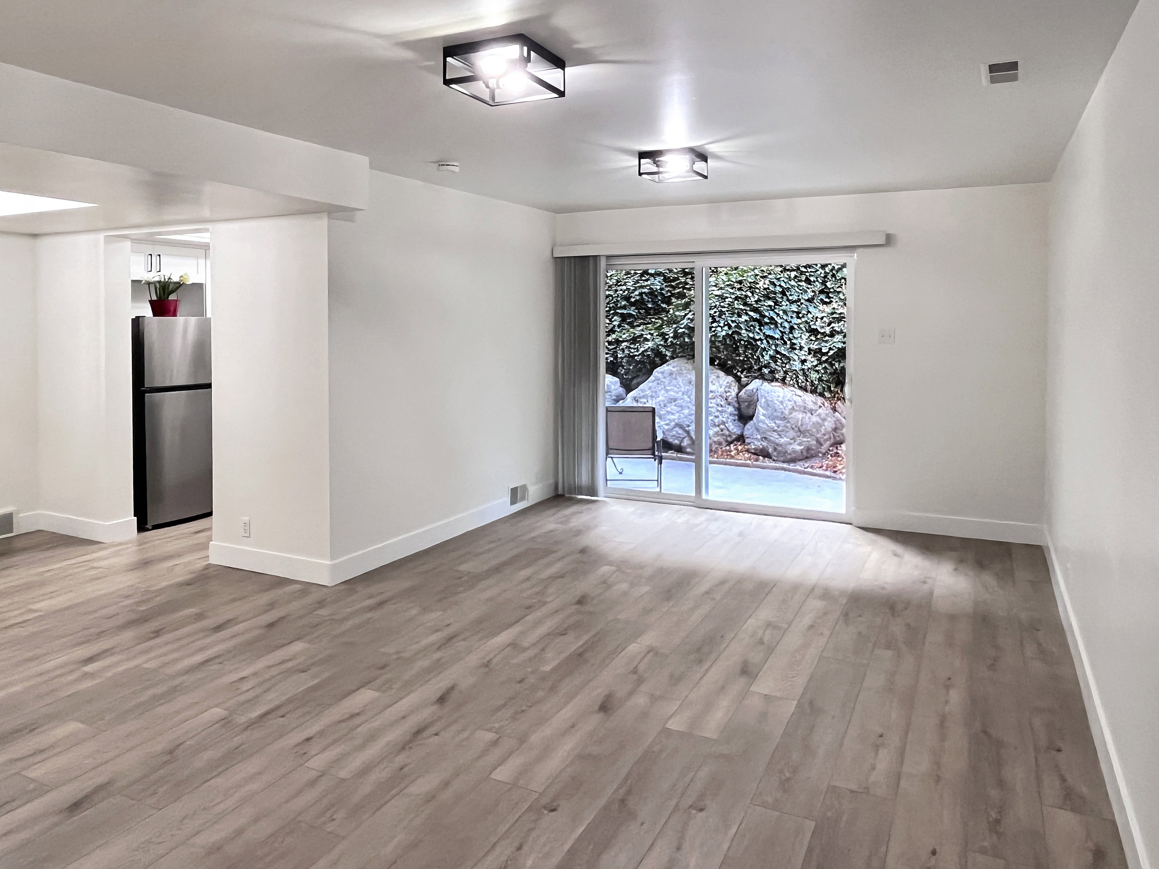 Living room featuring warm tones, fresh wood style flooring and newly painted timeless two-toned paint with large, modern baseboards