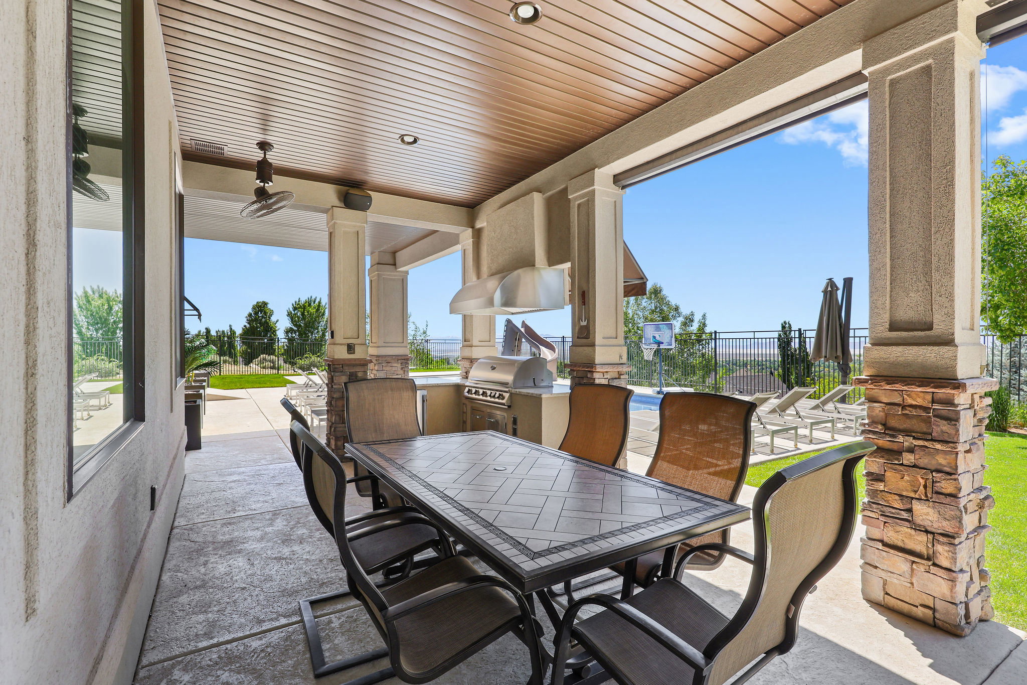 Covered patio featuring an outdoor kitchen with built-in grill and range hood, recessed lighting, ceiling fan, and textured concrete flooring