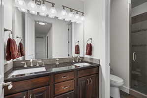 Double vanity featuring dark wood cabinetry, dual undermount sinks, and a dark countertop with a tiled backsplash