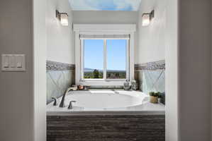 Built-in soaking tub with brushed nickel fixtures, bordered by a tiled surround featuring a mosaic accent strip